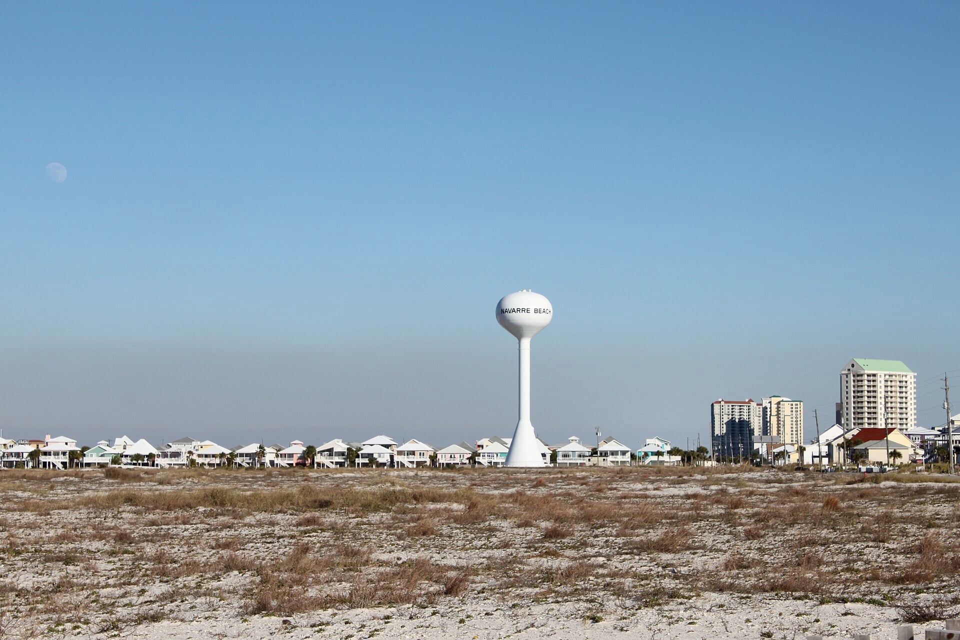 La torre de agua blanca de Navarre Beach sobre dunas bajas y casas de playa