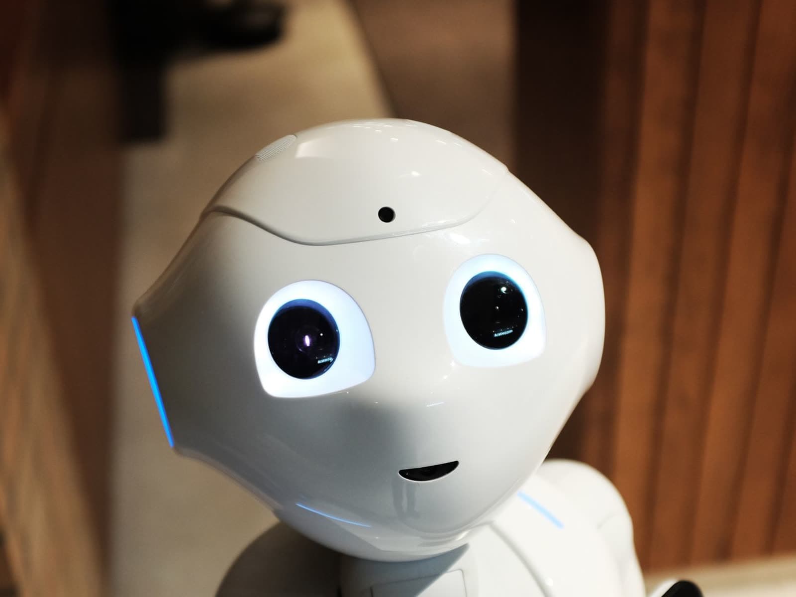 A white greeting and wayfinding robot with a friendly face in a building lobby