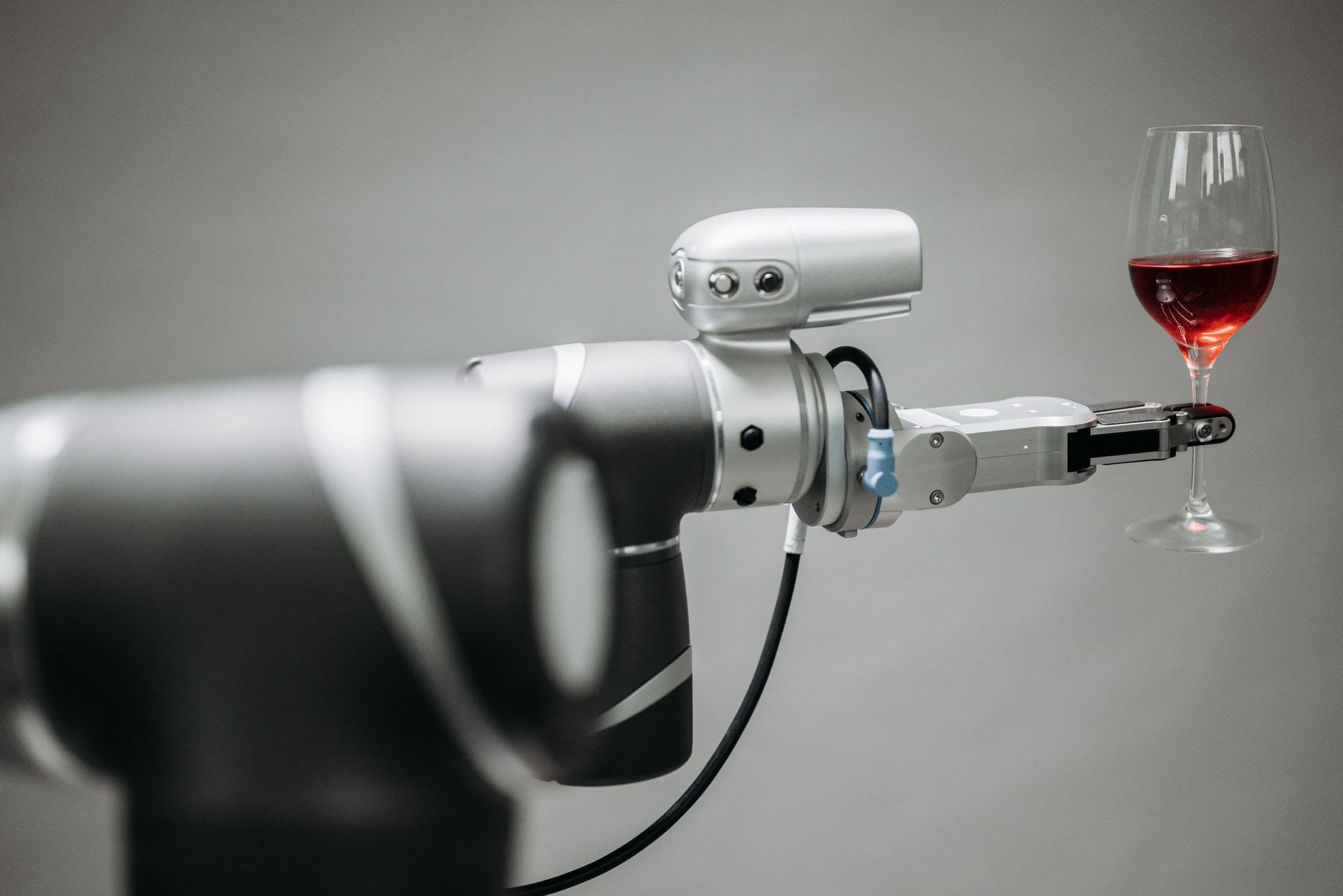 A collaborative robot arm holding a glass with a precise gripper