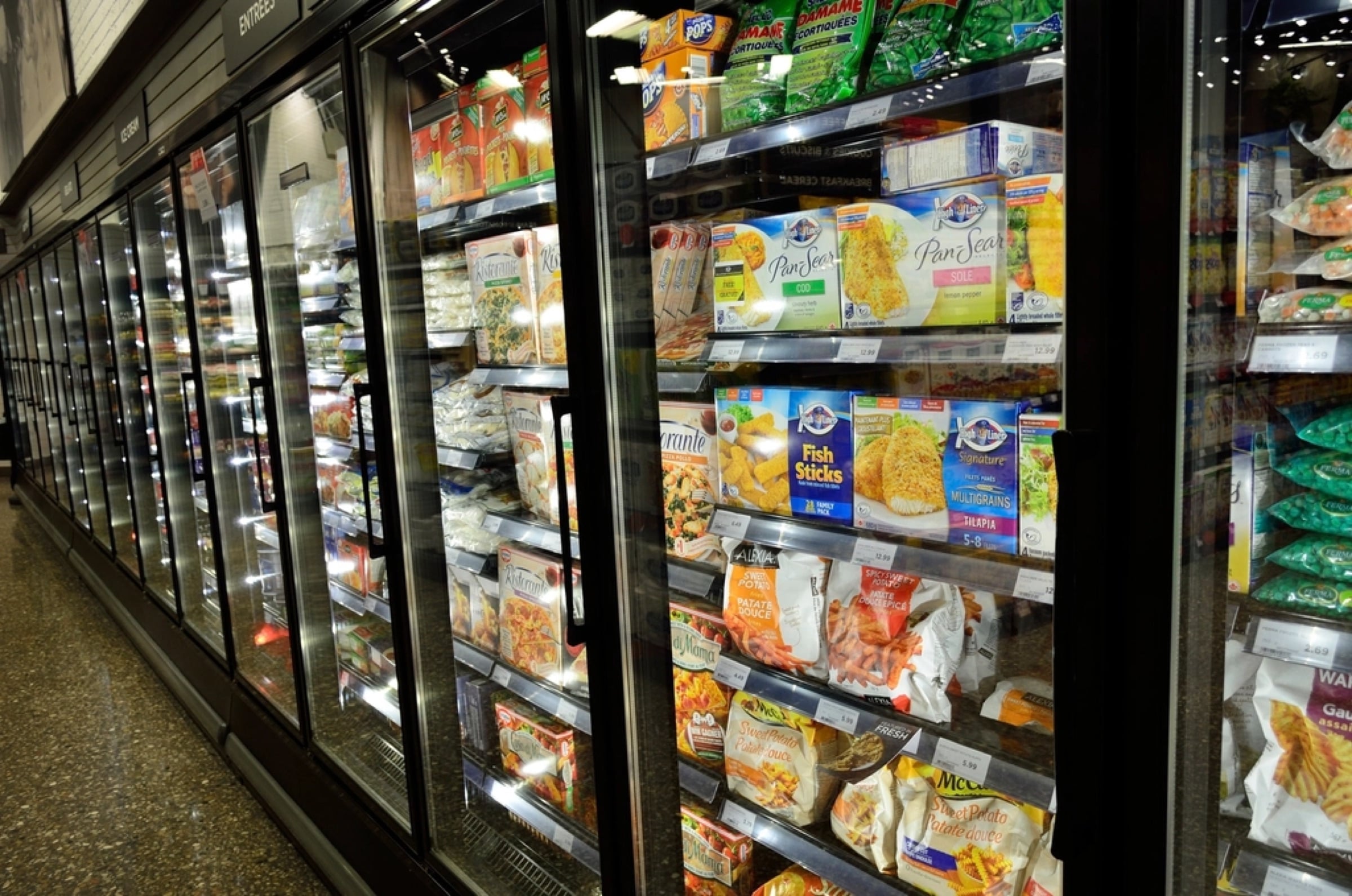 Un pasillo de congelados con refrigeradores de puerta de cristal