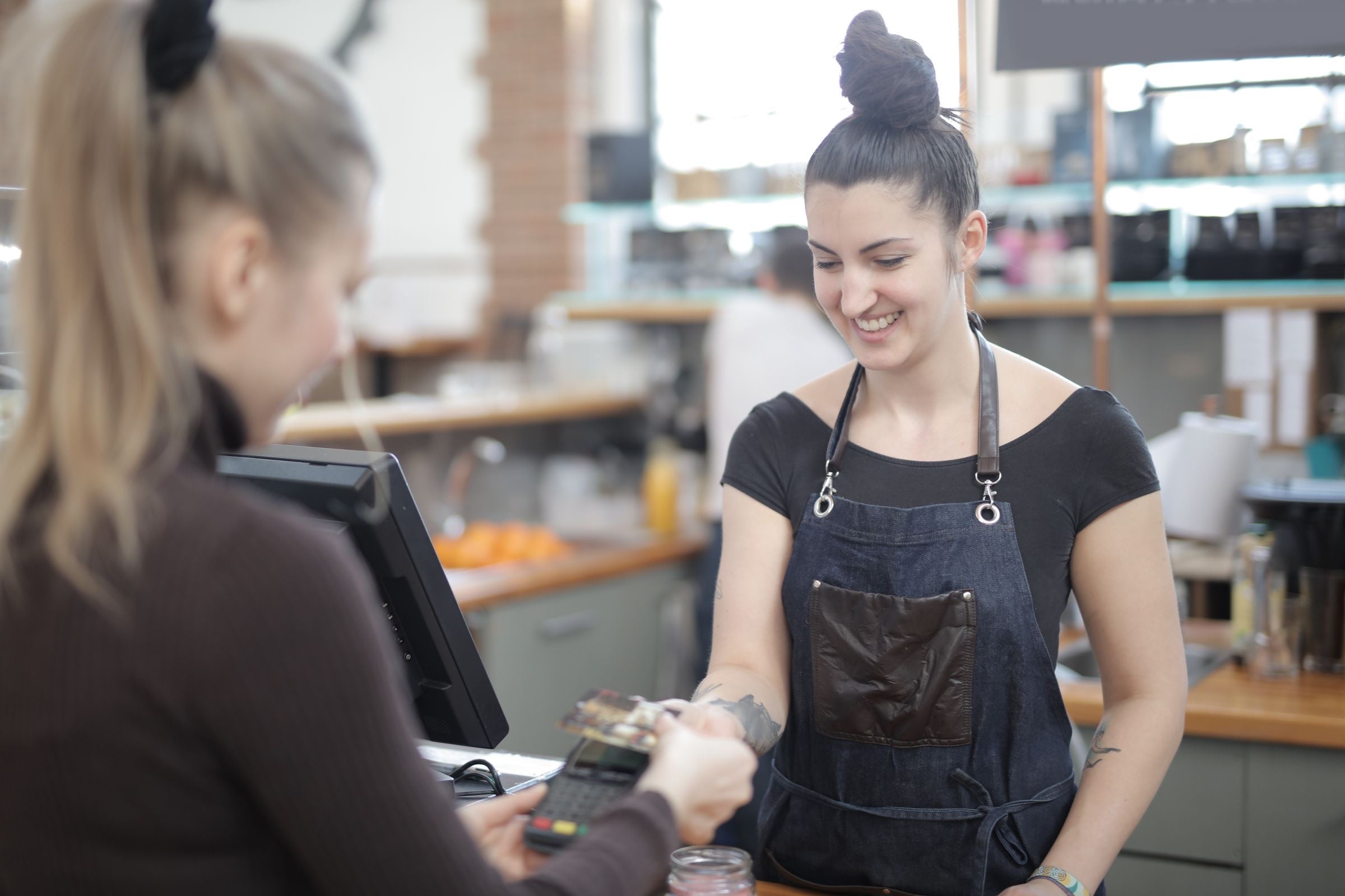 Una cajera sonriente atiende el pago de un cliente en el mostrador